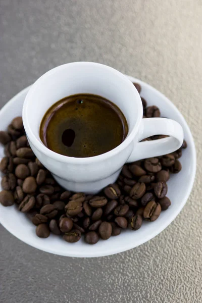 Espresso coffee. Coffee beans on a saucer and a small white cup — Stock Photo, Image