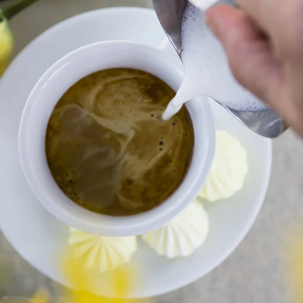 Kopi minum cappuccino dalam cangkir putih di atas meja di sebuah kafe di samping bunga kuning gorse dan tulip — Stok Foto