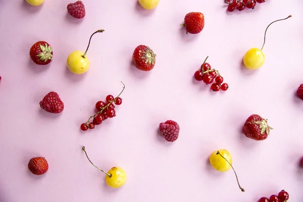 Les baies d'été sont éparpillées sur un fond rose - groseilles, cerises, framboises et fraises — Photo