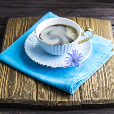 Sıcak bir içecek bir fincan yanındaki mavi hindiba çiçek