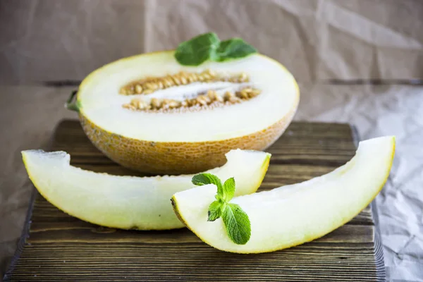 Melón rebanado junto con menta en un soporte de madera — Foto de Stock