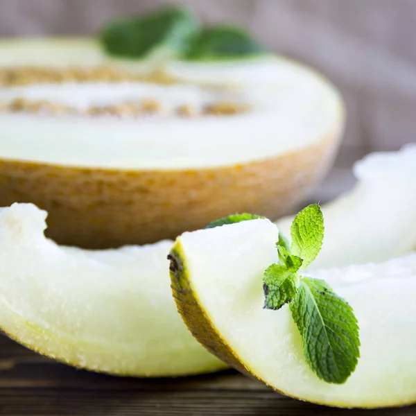 Melón rebanado junto con menta en un soporte de madera — Foto de Stock