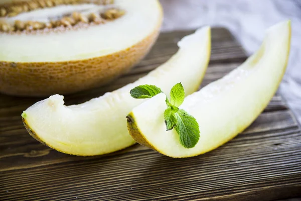 Melón rebanado junto con menta en un soporte de madera — Foto de Stock