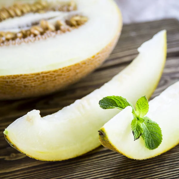 Melón rebanado junto con menta en un soporte de madera — Foto de Stock