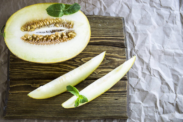 Melon sliced along with mint on a wooden stand
