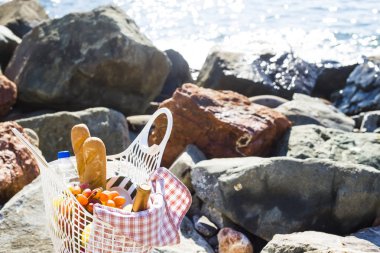 Deniz kenarında üzüm, elma, armut, baget ekmek, şarap ve bir sepet ile yorgan üzerinde dinlenmek