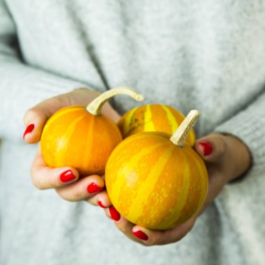 Kırmızı manikür kızla birkaç küçük kabak elinde tutar.