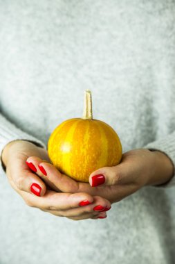 Kırmızı manikür kızla bir kabak elinde tutar.