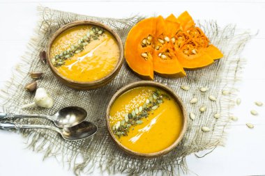 balkabağı çorbası bir kil tabak kabak çekirdeği, susam, baharat ve krema ile dekore edilmiş