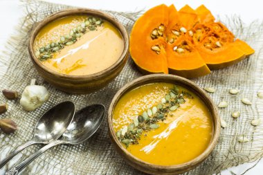 balkabağı çorbası bir kil tabak kabak çekirdeği, susam, baharat ve krema ile dekore edilmiş