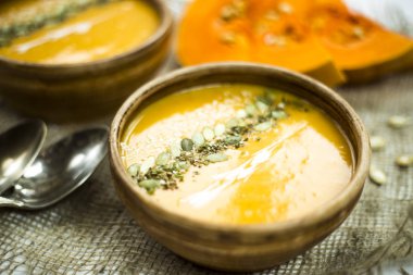 balkabağı çorbası bir kil tabak kabak çekirdeği, susam, baharat ve krema ile dekore edilmiş