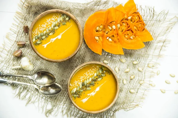 Тыквенный суп в глиняном блюде, украшенном семенами тыквы, кунжутом, специями и сливками — стоковое фото