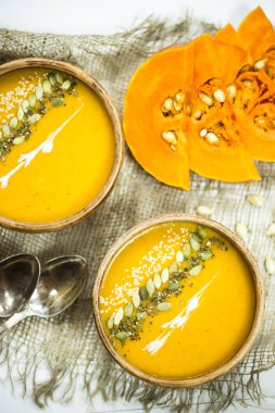 balkabağı çorbası bir kil tabak kabak çekirdeği, susam, baharat ve krema ile dekore edilmiş