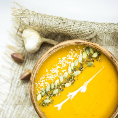 balkabağı çorbası bir kil tabak kabak çekirdeği, susam, baharat ve krema ile dekore edilmiş