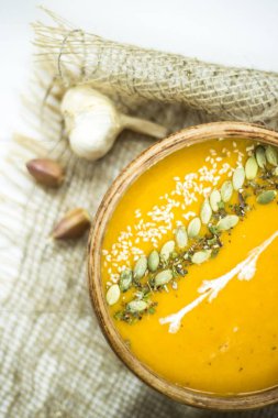 balkabağı çorbası bir kil tabak kabak çekirdeği, susam, baharat ve krema ile dekore edilmiş