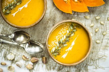 balkabağı çorbası bir kil tabak kabak çekirdeği, susam, baharat ve krema ile dekore edilmiş