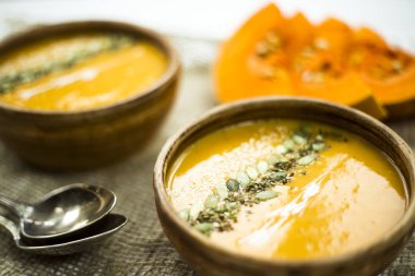 balkabağı çorbası bir kil tabak kabak çekirdeği, susam, baharat ve krema ile dekore edilmiş