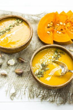balkabağı çorbası bir kil tabak kabak çekirdeği, susam, baharat ve krema ile dekore edilmiş
