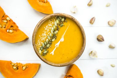 balkabağı çorbası bir kil tabak kabak çekirdeği, susam, baharat ve krema ile dekore edilmiş