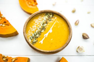 balkabağı çorbası bir kil tabak kabak çekirdeği, susam, baharat ve krema ile dekore edilmiş