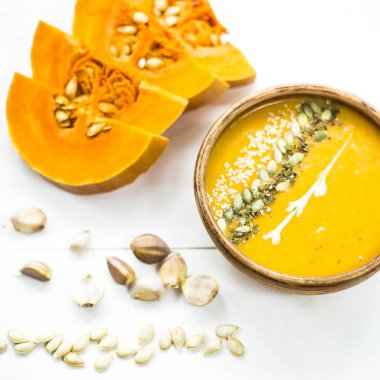 balkabağı çorbası bir kil tabak kabak çekirdeği, susam, baharat ve krema ile dekore edilmiş