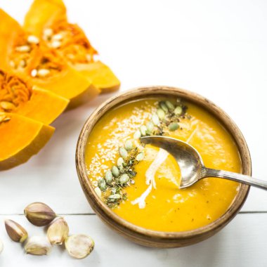 balkabağı çorbası bir kil tabak kabak çekirdeği, susam, baharat ve krema ile dekore edilmiş