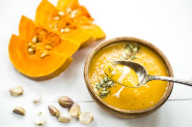 balkabağı çorbası bir kil tabak kabak çekirdeği, susam, baharat ve krema ile dekore edilmiş