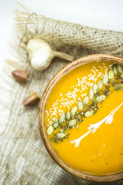 balkabağı çorbası bir kil tabak kabak çekirdeği, susam, baharat ve krema ile dekore edilmiş