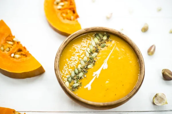 balkabağı çorbası bir kil tabak kabak çekirdeği, susam, baharat ve krema ile dekore edilmiş