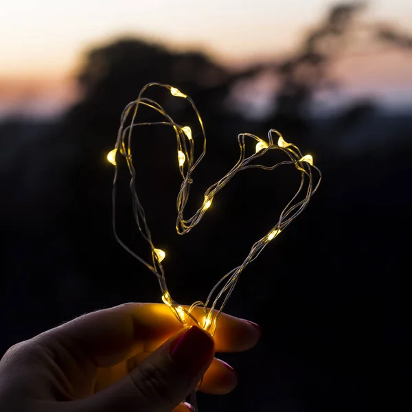 El símbolo del amor - el corazón de la guirnalda en las manos — Foto de Stock