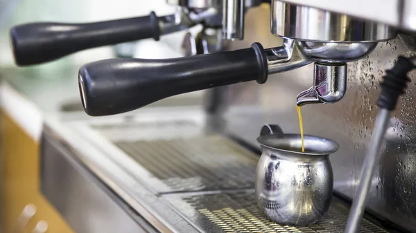 make espresso with a coffee machine. Fresh coffee goes from machine to metal jug