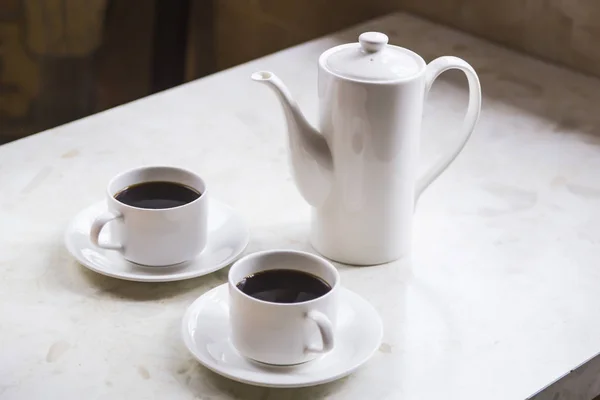 Minimalism in the kitchen - white cups and a teapot with black coffee