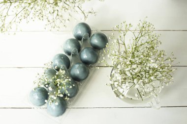 Gypsophila demetleri arasında beyaz bir masada mavi Paskalya yortusu yumurta