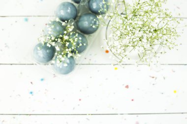 Gypsophila demetleri arasında beyaz bir masada mavi Paskalya yortusu yumurta