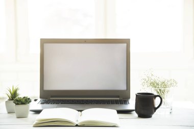 Beyaz masa üstünde bir defter ile laptop monitör işyerinde. Minimalist tasarımı. Güneş ışığı - kolay renklendirme