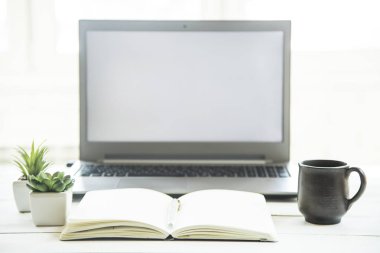 Beyaz masa üstünde bir defter ile laptop monitör işyerinde. Minimalist tasarım
