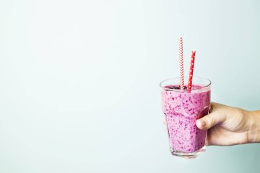 Muz Frenk üzümü smoothies elinde mavi bir arka plan üzerinde kırmızı payet ile mor renk. Sağlıklı gıda ve beslenme kavramı. Arka plan, boşaltmak