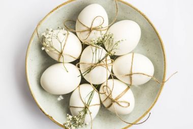 Paskalya yumurtaları minimalistically beyaz zemin üzerinde mavi bir yuvarlak tabak sicim ve gypsophila çiçeklerle dekore edilmiştir. Üstten Görünüm, düz yatıyordu