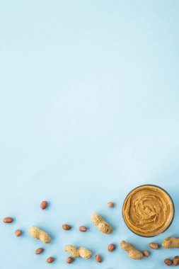 Bir kavanoz fıstık kabuğu ve olmadan arasında fındık hamur mavi bir arka plan üzerinde. Vegan ürün. Amerikan kahvaltı. Üstten Görünüm, düz lay, boşaltmak