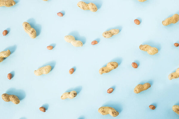 Целые арахис в скорлупе и арахис, очищенный на синем фоне. Концепция здорового веганского питания. Плоский, вид сверху
