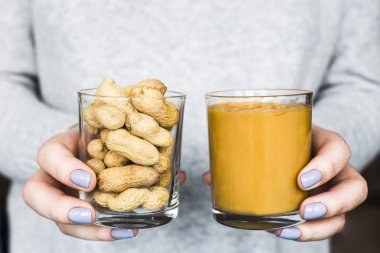 Kadın onun elinde iki kavanoz - fıstık kabuğu ve fıstık ezmesi ile tutuyor. Vegan ve doğal gıda kavramı