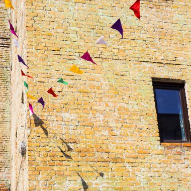 Eski loft tuğla binalar büyük pencereler ile arka plan üzerinde renkli üçgen dekoratif bayrakları asmak. Arka plan, boşaltmak