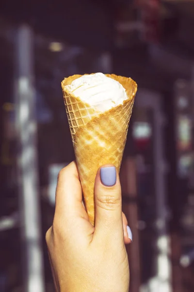 アイス クリーム ボール ぼやけた街を背景に女性の手でワッフル ホーンに密閉します 夏の冷たいデザートのコンセプト — ストック写真