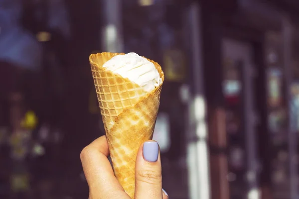 アイス クリーム ボール ぼやけた街を背景に女性の手でワッフル ホーンに密閉します 夏の冷たいデザートのコンセプト — ストック写真