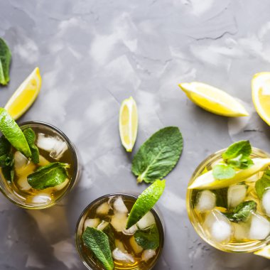 Buz, nane ve limon gri beton zemin üzerine soğuk çayla birkaç cam gözlükler. Yaz soğutma içeceği. Üstten Görünüm, düz yatıyordu, boşaltmak