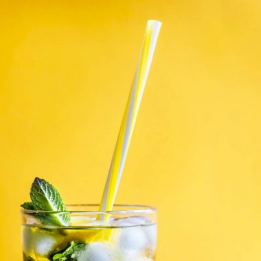 Buzlu çay buz, limon ve nane kombine renkli sarı bir arka plan üzerinde. Yaz soğuk içki kokteyl