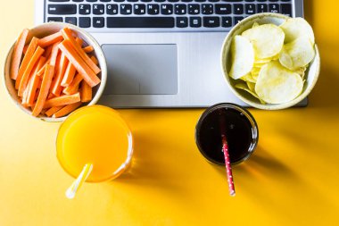 Atıştıracak bir şeyler - sağlıklı beslenme havuç suyu ile veya zararlı gıda Cips kola seçin. Bir dizüstü bilgisayarda çalışan arasında tatilinde gıda