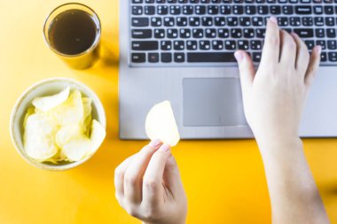 Cips ve cola laptop vardır. Bir kadın sağlıksız abur cubur lazım. İş arasındaki tatilinde snack