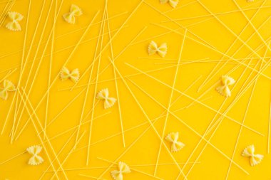 Spagetti makarna sarı bir arka plan üzerinde dağınık olduğunu. Üstten Görünüm, düz yatıyordu