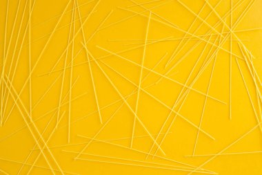 Spagetti makarna sarı bir arka plan üzerinde dağınık olduğunu. Üstten Görünüm, düz yatıyordu